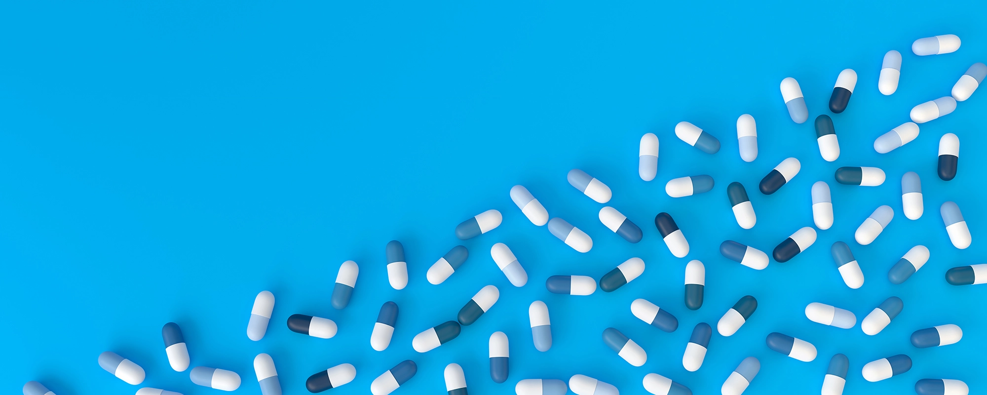 many blue pills diagonally poured on a blue background