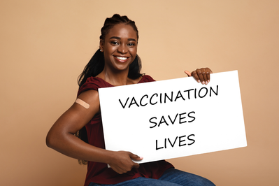 woman holding sign that says vaccination saves lives